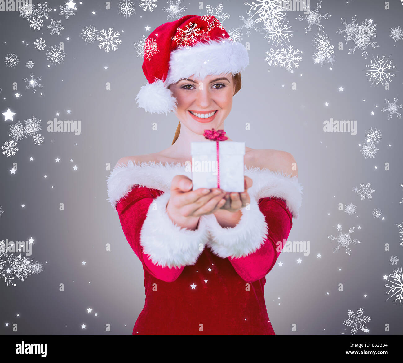 Zusammengesetztes Bild von hübschen Mädchen in Santa Kostüm mit Geschenk-box Stockfoto