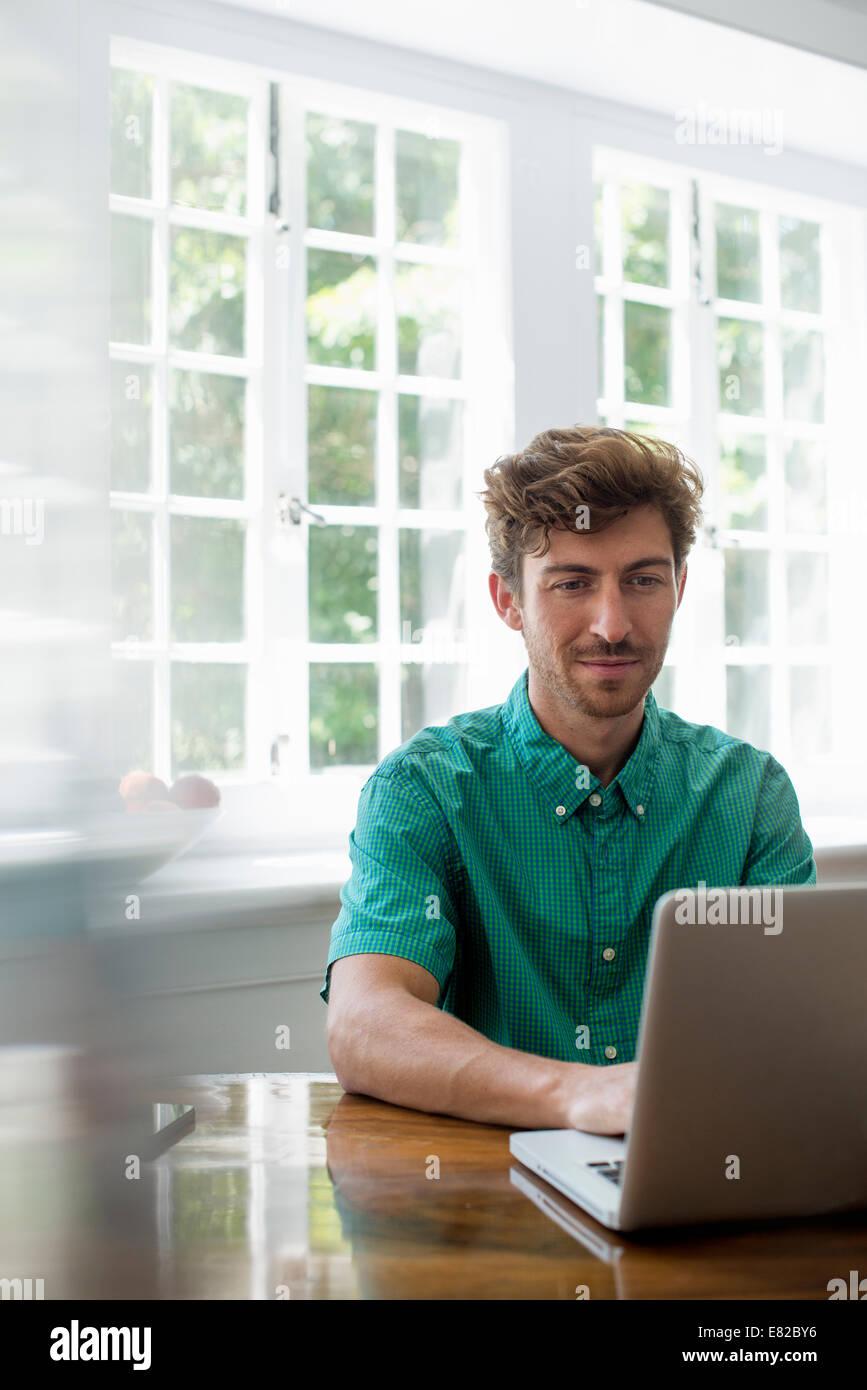 Ein Mann sitzt an einem Tisch mit einem Laptop. Arbeiten von zu Hause aus. Stockfoto