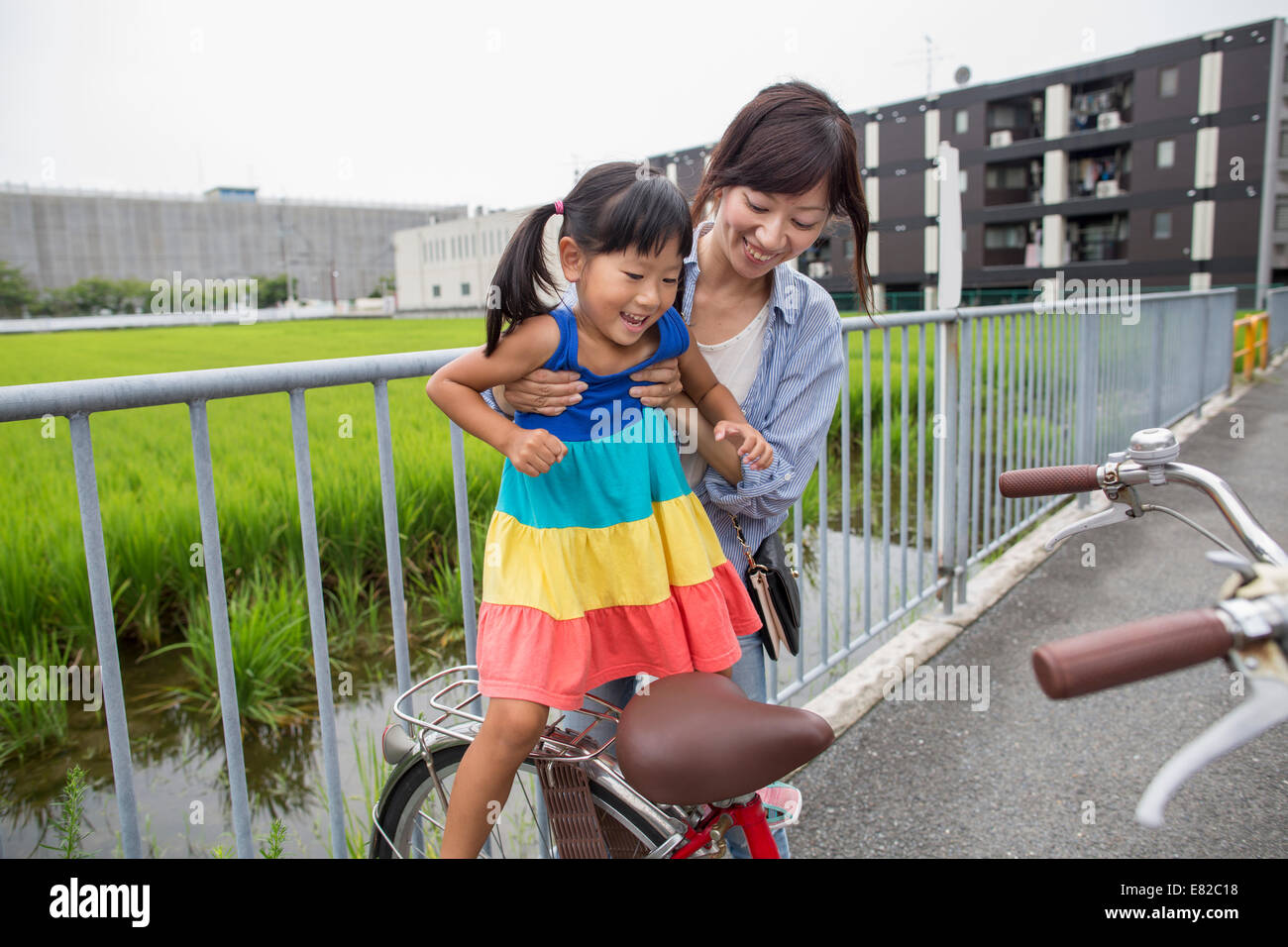 Eine Mutter, die Aufhebung ihrer Tochter auf einem Fahrrad. Stockfoto