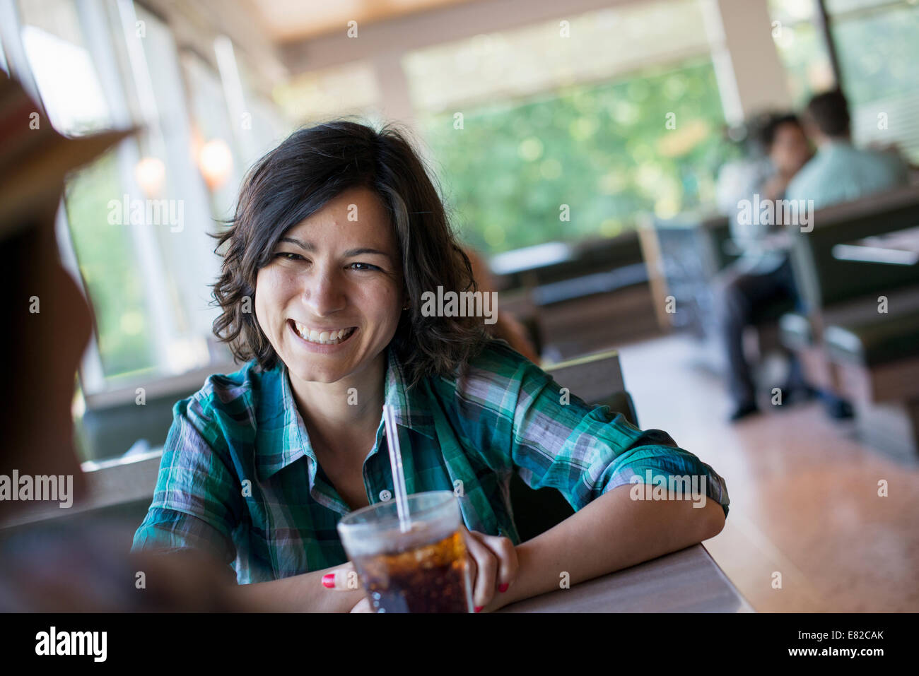 Eine Frau sitzend ein kühles Getränk an einem Diner Tisch halten. Stockfoto