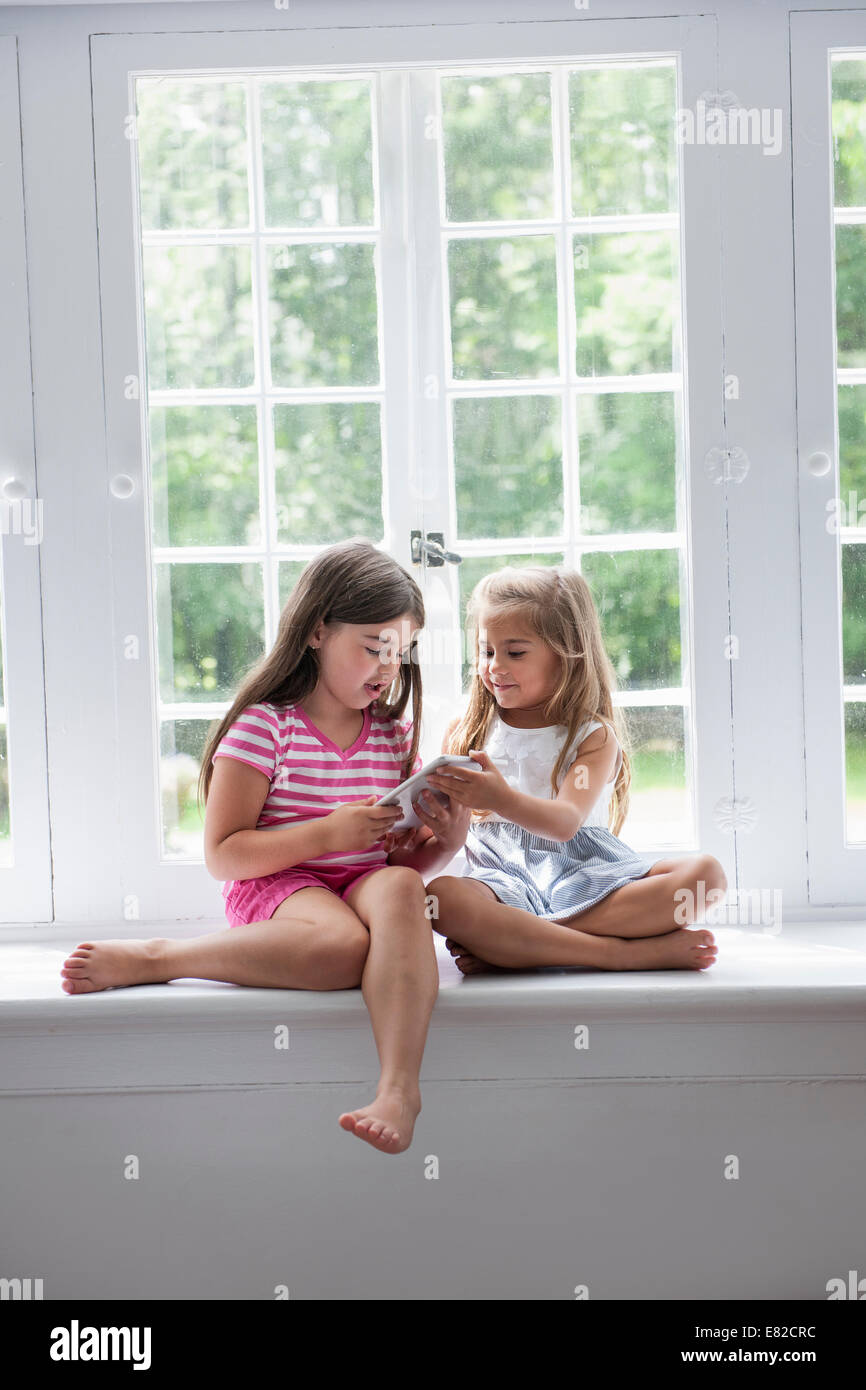 Zwei Mädchen spielen, teilen eine digitale-Tablette. Stockfoto