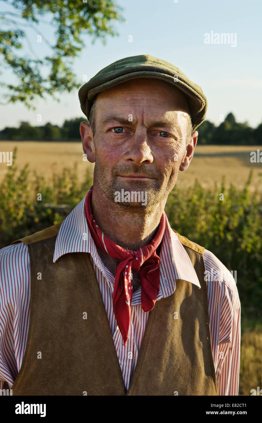 Ein Mann mit einem roten Halstuch und flachen Hut, Arbeitshemd und Weste. Stockfoto