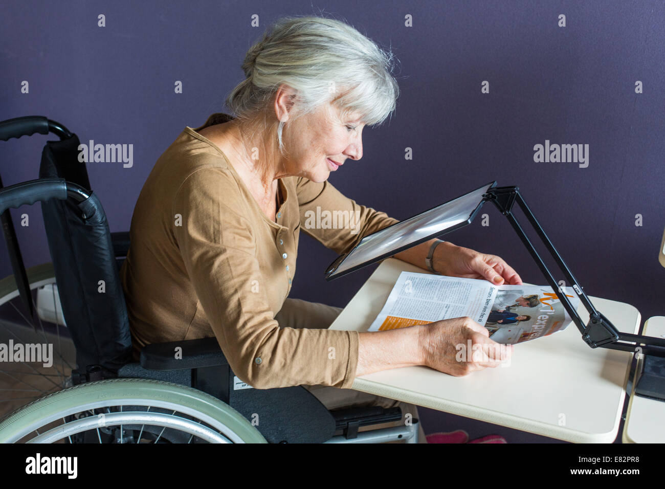 Frau mit einer riesigen Lupe für Menschen mit Sehbehinderung beleuchtet. Stockfoto