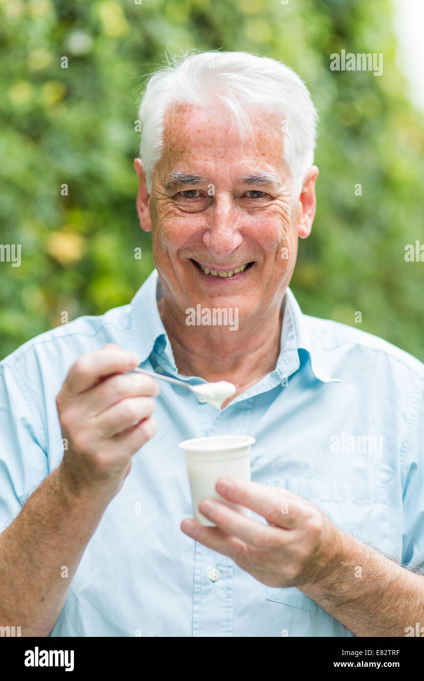 Mann isst Joghurt. Stockfoto