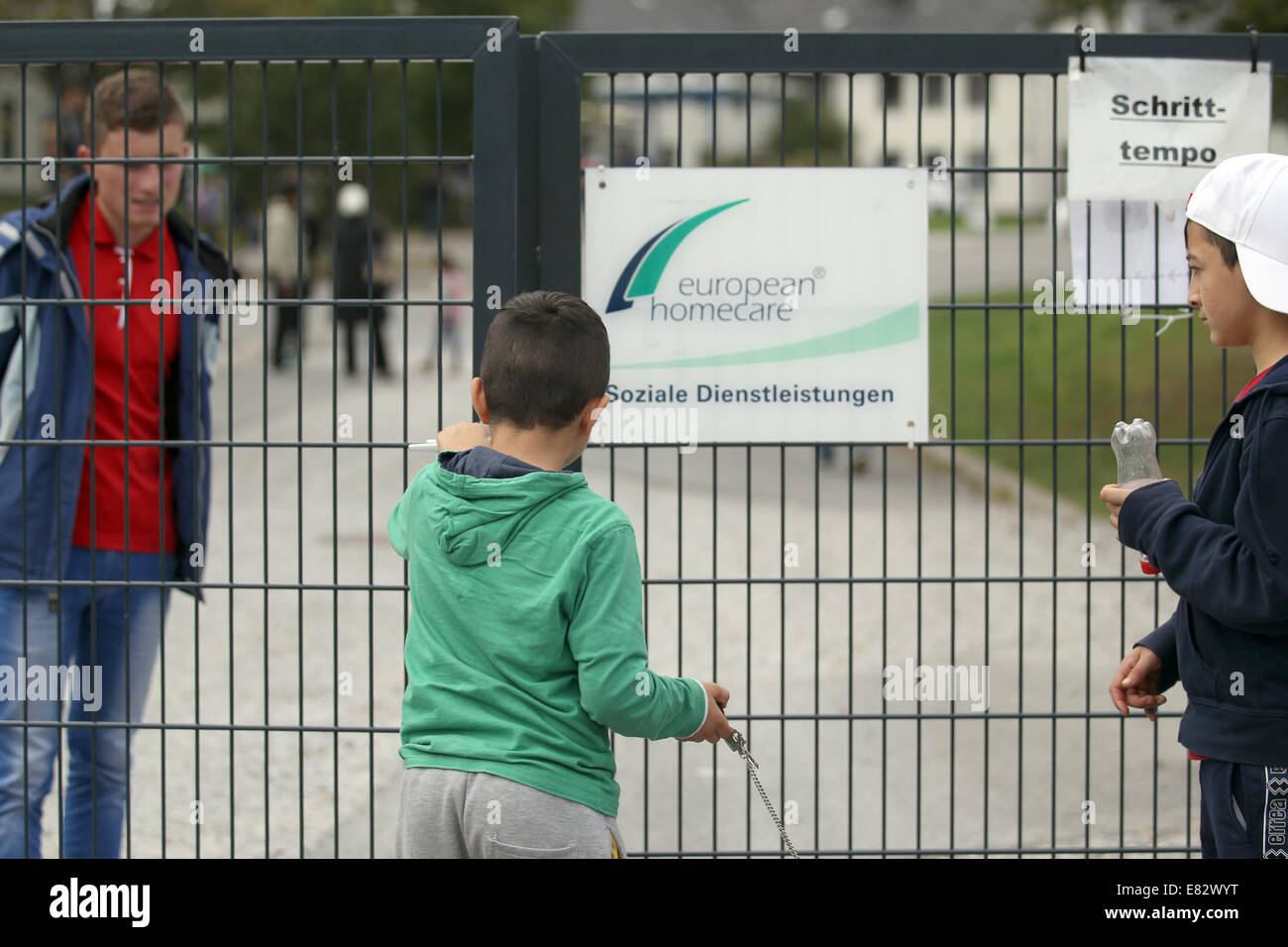 Burbach, Deutschland. 29. Sep, 2014. Ein Junge wird einen Tor des ehemaligen Siegerland-in Burbach, Deutschland, 29. September 2014 Kaserne geschlossen. Gewalttätige Übergriffe von Flüchtlingen durch Mitarbeiter einer privaten Sicherheitsfirma sollen in einem Flüchtlingsheim in Burbach stattgefunden haben. Siegerland-Kaserne dient derzeit als Notunterkünfte für Asylbewerber und Flüchtlinge. Foto: INA FASSBENDER/DPA/Alamy Live-Nachrichten Stockfoto