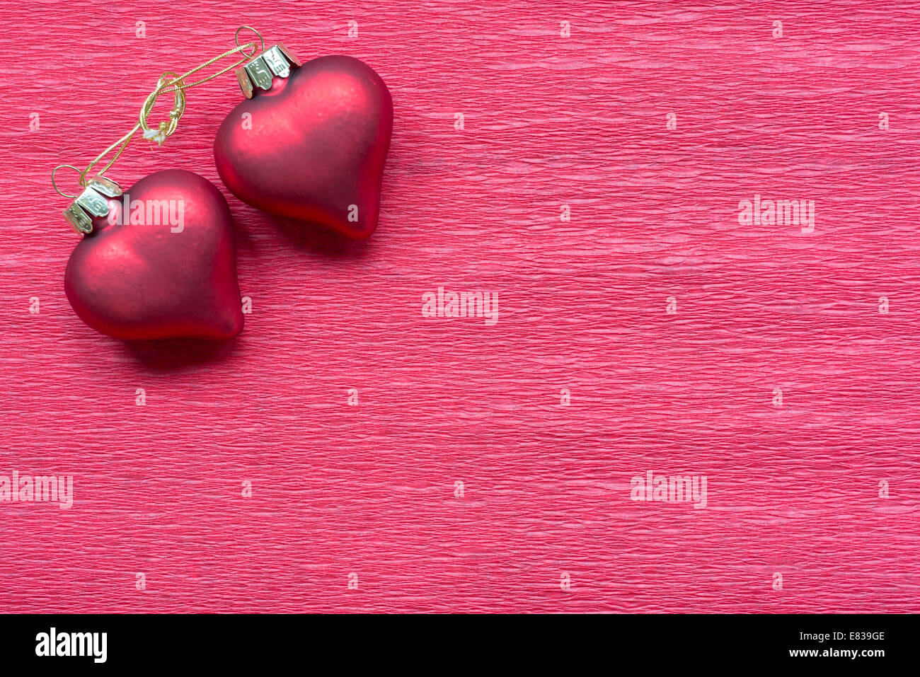 zwei verknüpfte Herzen auf rotem Papierhintergrund Stockfoto