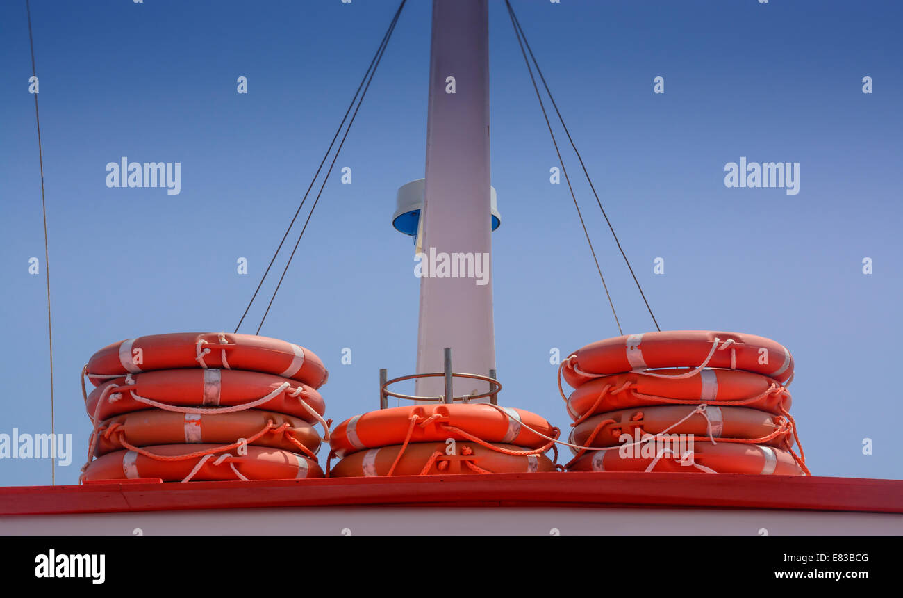 Rettungsringe in der Farbe orange gestapelt auf einem Boot mit blauem Himmel, Werbefläche. Stockfoto