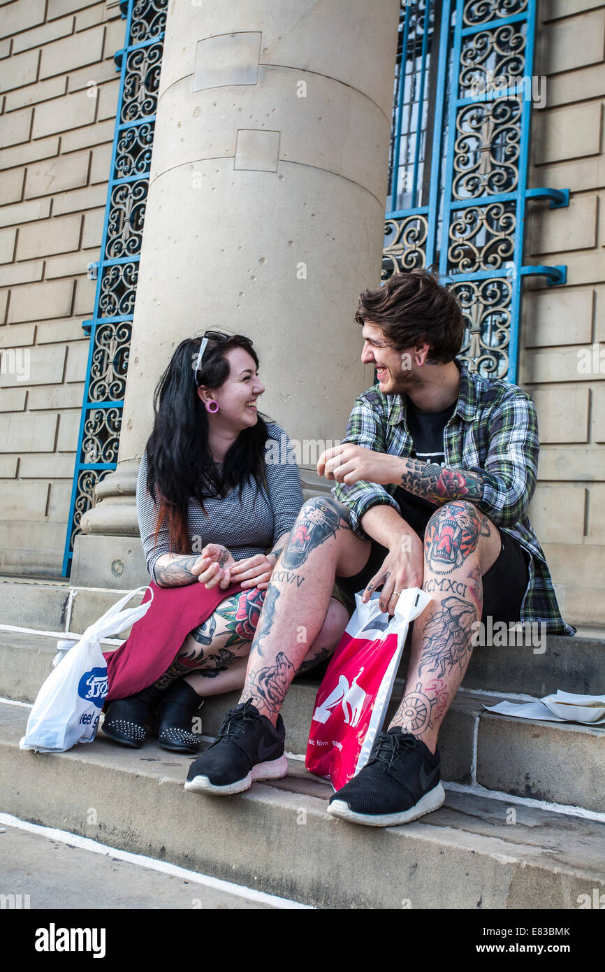 Ein junges Paar mit Tattoos sitzen auf Treppe im Rathaus in Sheffield City Centre UK Stockfoto