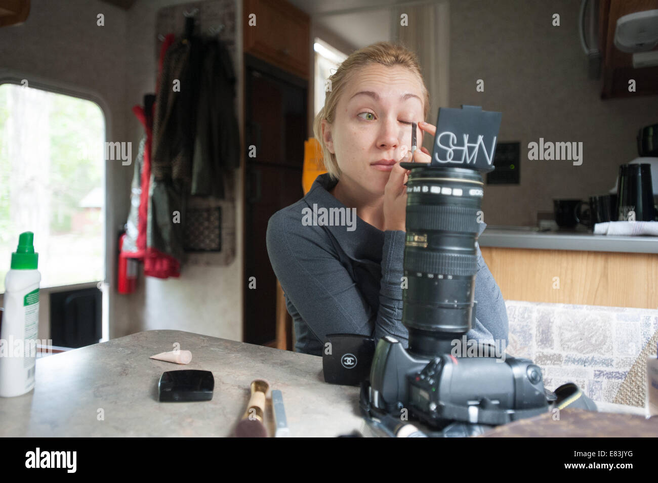 Modell gilt Make-up in RV mit Kamera als Spiegelsystem Stockfoto