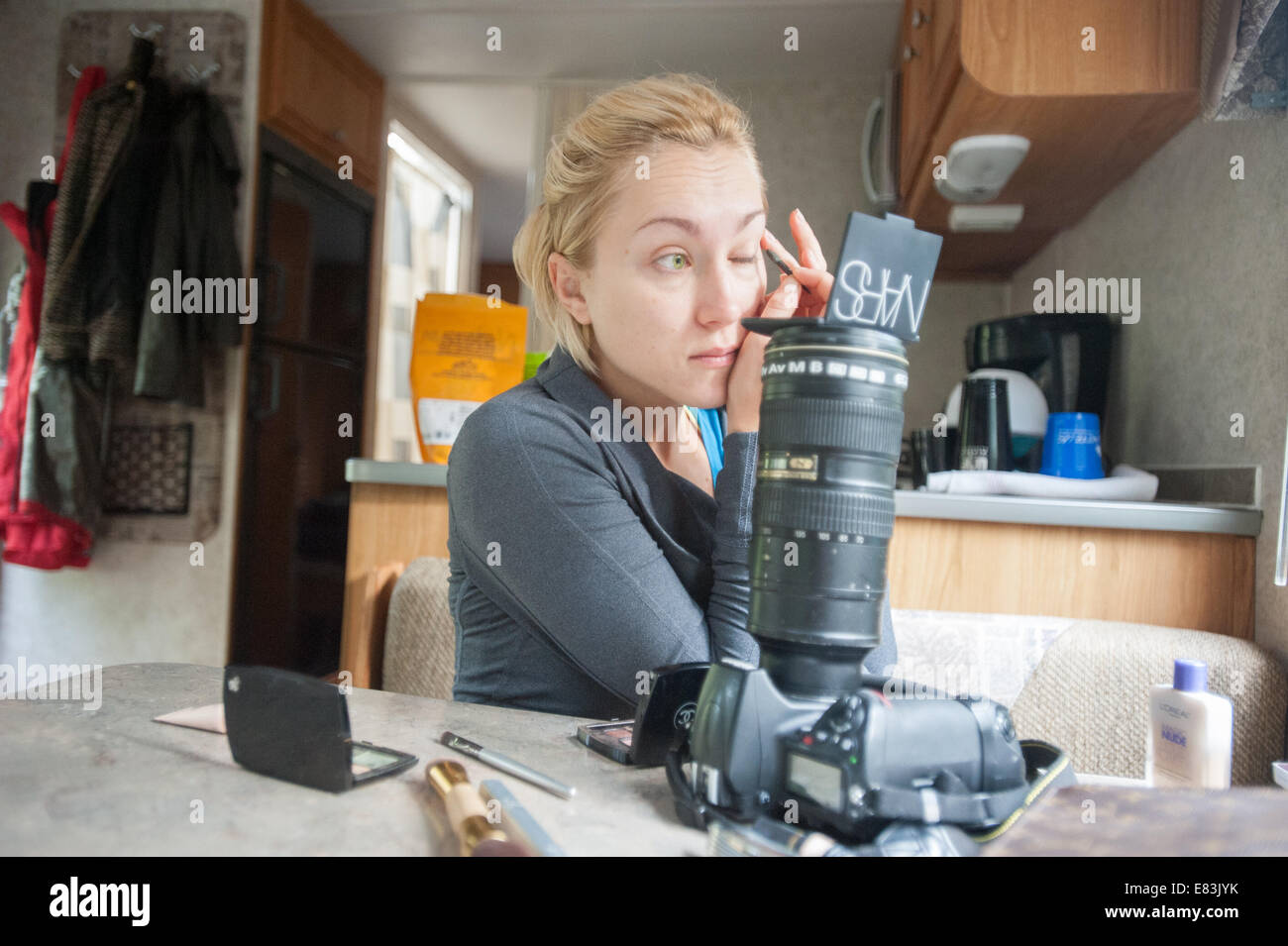 Modell gilt Make-up in RV mit Kamera als Spiegelsystem Stockfoto