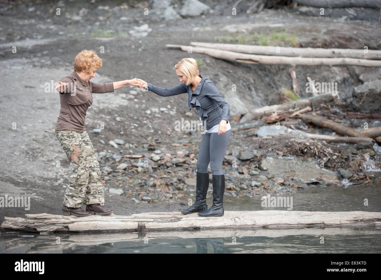Mutter und Tochter-Kreuzung-Stream auf Log in Alaska Stockfoto