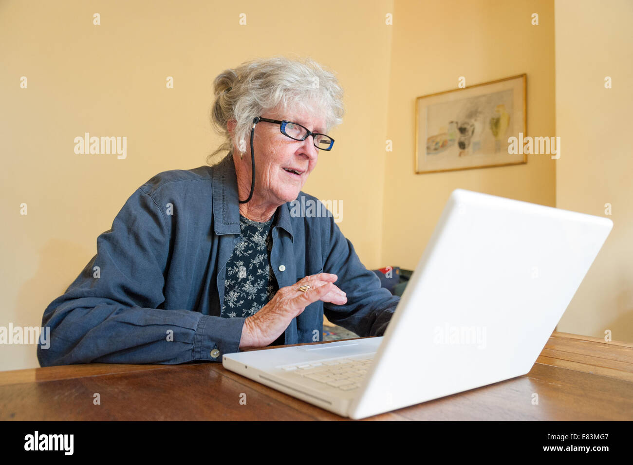 Ältere Frau Surfen Internet auf AppIe Laptop-Computer zu Hause, UK Stockfoto