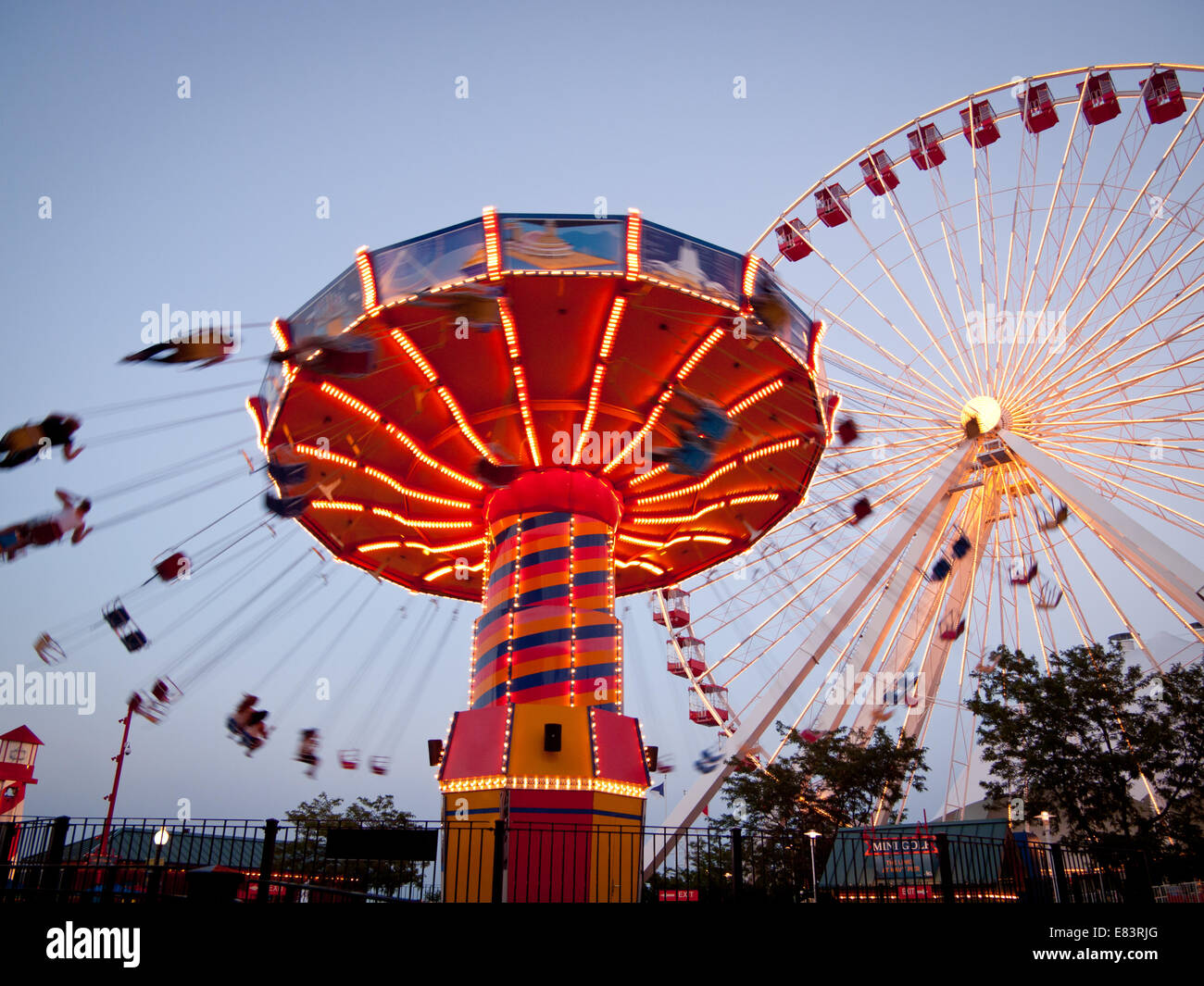 Ein Blick auf die Wave Swinger und Riesenrad fährt am Navy Pier, einem beliebten Vergnügungspark in Chicago, Illinois. Stockfoto