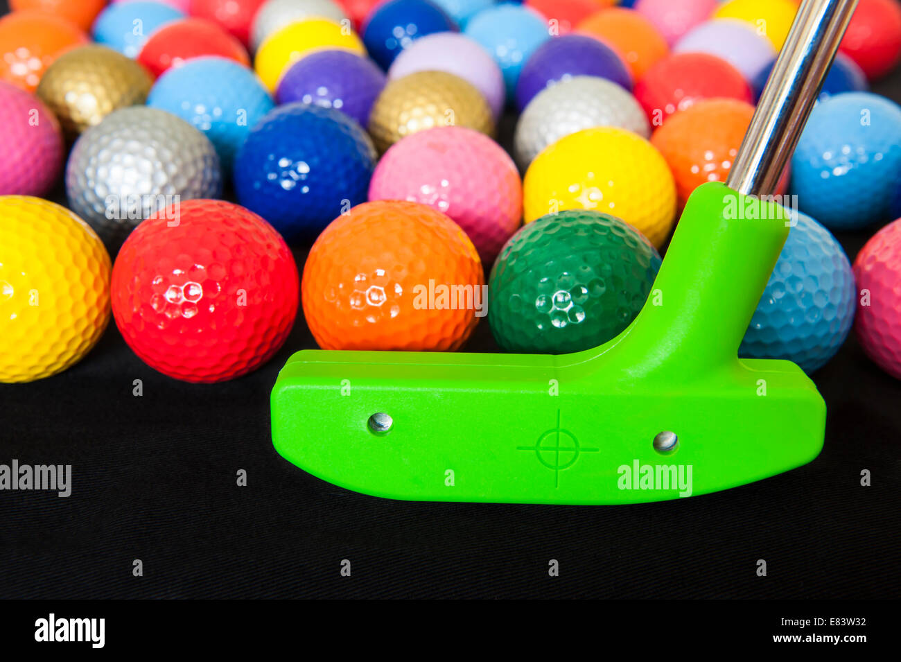 Bunte Mini-Golfbälle mit einem grünen club Stockfoto