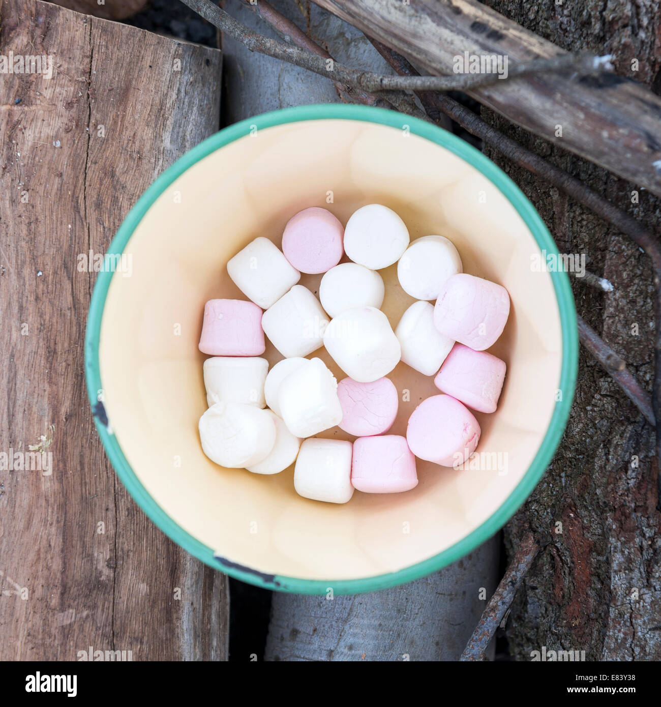 Marshmallows in rosa und weiß in eine alte Schüssel auf Brennholz, camping Stockfoto
