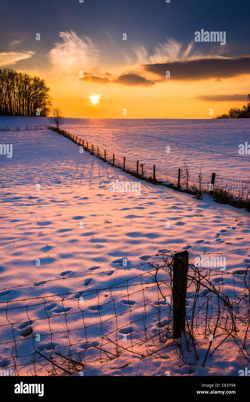 Sonnenuntergang über einen Zaun in ein Schnee bedeckt Feld-Hof in ländlichen Carroll County, Maryland. Stockfoto