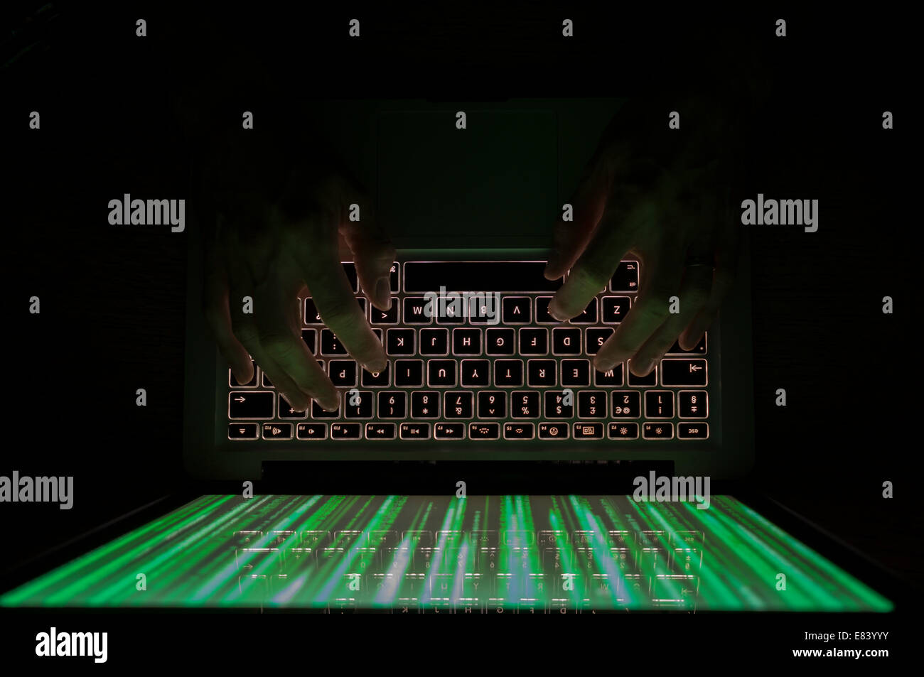 Computer Hacker die Eingabe über Tastatur mit grünen Matrix style Grafiken auf dem Monitor Stockfoto