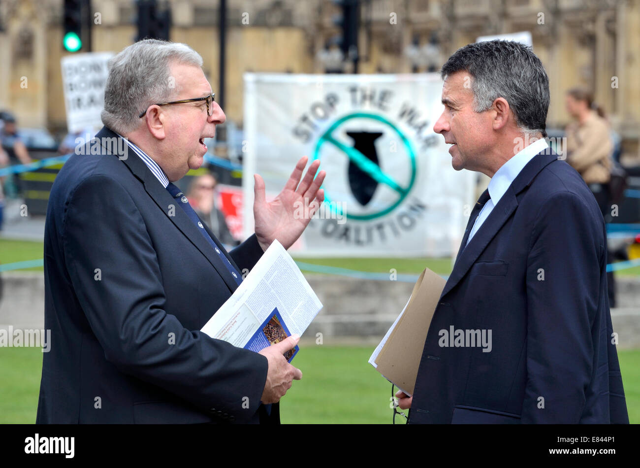 Keith Simpson MP Gespräch mit Bernard Jenkin MP (beide konservativ) am College Green Westminster - Stop The War Coalition banner Stockfoto