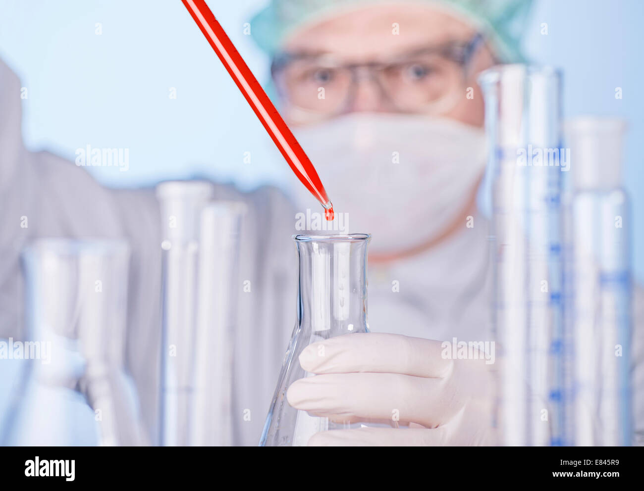 Wissenschaftler in einem Glaskolben eine rote Flüssigkeit aus einer Pipette Tropfen. Stockfoto