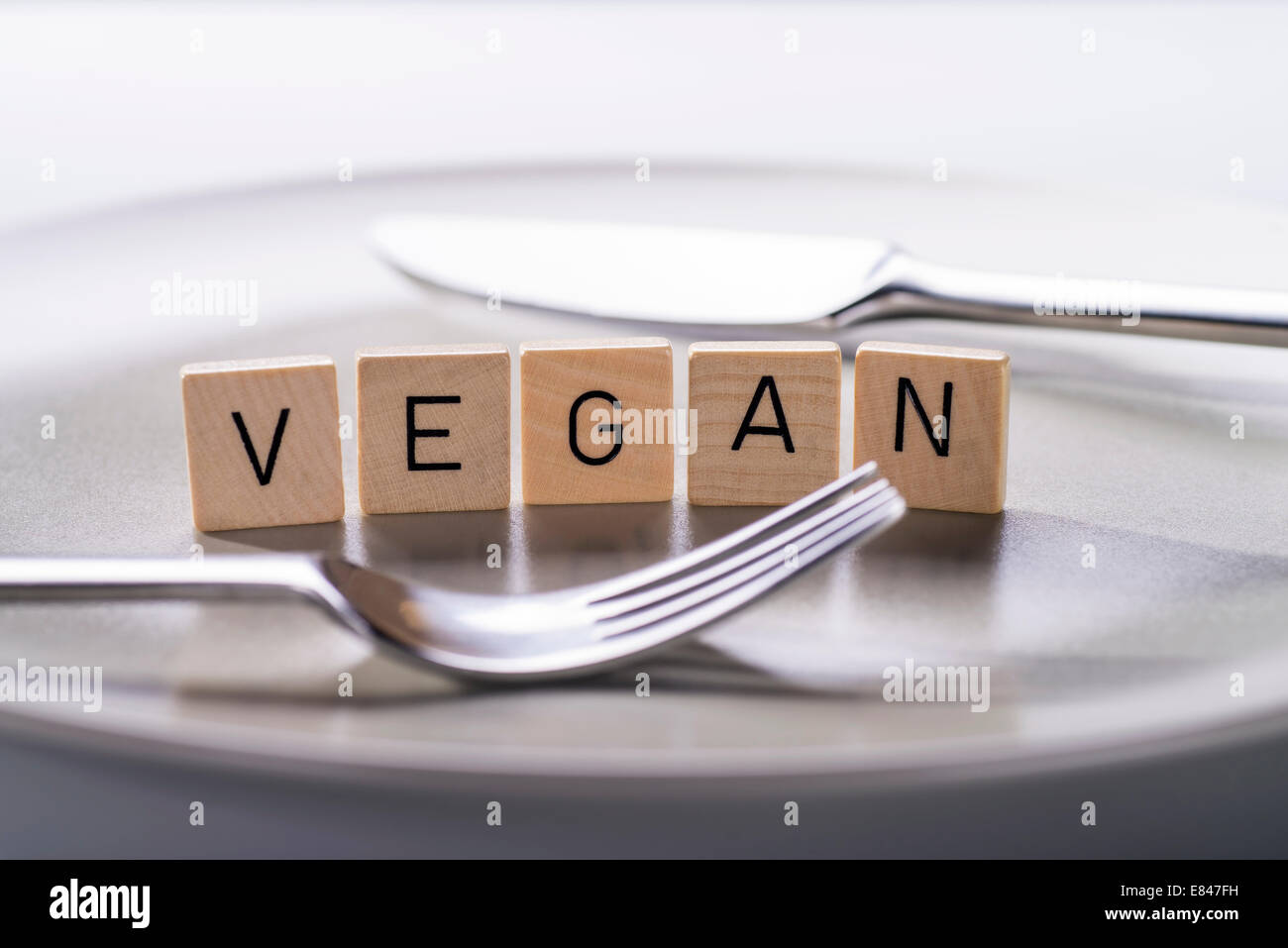 Teller mit Messer und Gabel und das Wort "Vegan". Stockfoto
