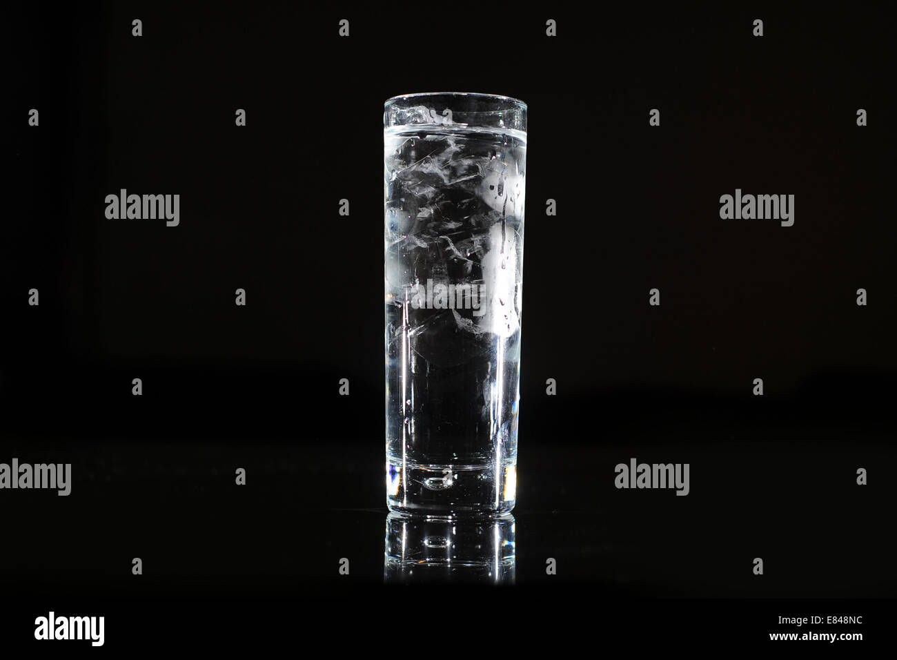 Ein Glas klares Trinkwasser aus einem Hahn vor einem schwarzen Hintergrund. Stockfoto