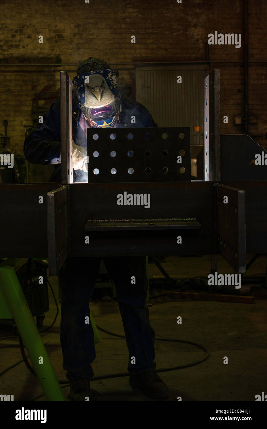 Ein Schweißgerät arbeitet auf einem strukturellen Balken in einer Gießerei Stanzerei. Stockfoto