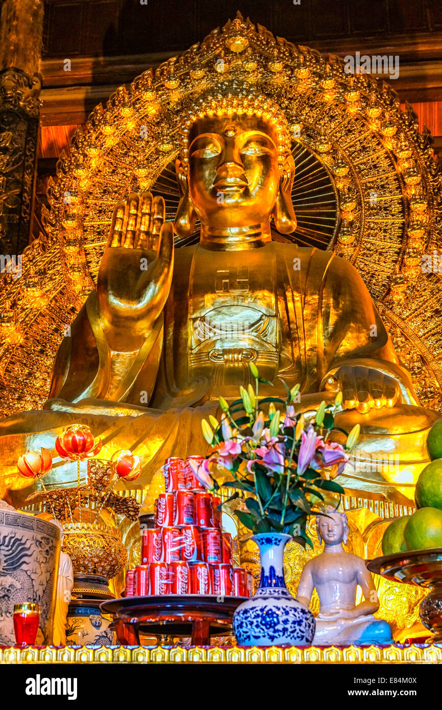 Chua Bai Dinh buddhistische Pagode: Stapel von roten Coca Cola Dosen vor riesigen goldenen Buddha. Stockfoto