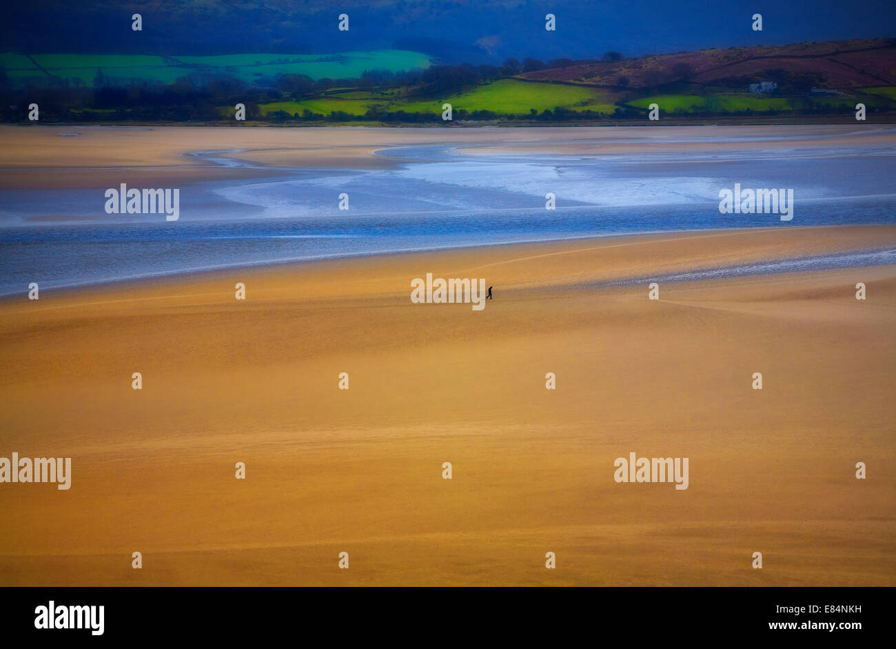 Einsamer Mann zu Fuß auf einen Sandstrand am Portmeirion - Standort für die 1960er Jahre Kultfilm "The Prisoner", Gwynedd, North Wales, UK Stockfoto