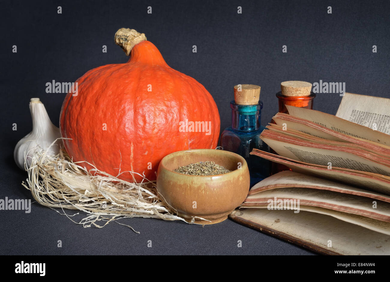 Kräuter in Keramik Tasse, Knoblauch, Kürbis, Halloween antike Apotheke Glas und buchen auf dunklem Hintergrund Stockfoto
