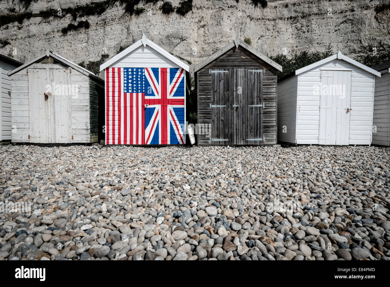Eine Strandhütte, gemalt mit den britischen und amerikanischen Flaggen, stehend gegen ihren Nachbarn im tristen und schmucklosen. Stockfoto