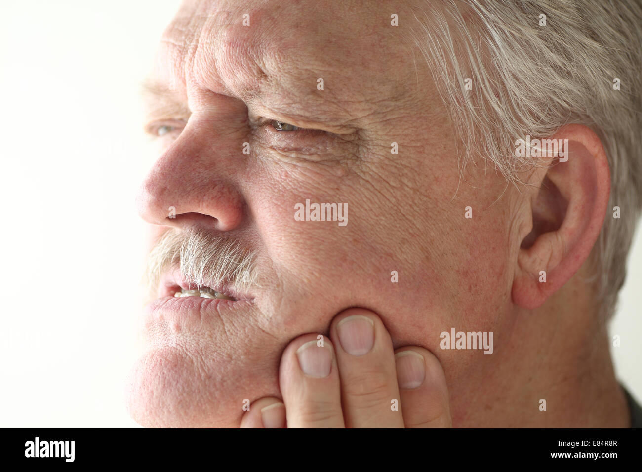 Bereich der Schmerzen zeigt Senior Mann auf seine Kiefer mit seinen Fingern. Stockfoto