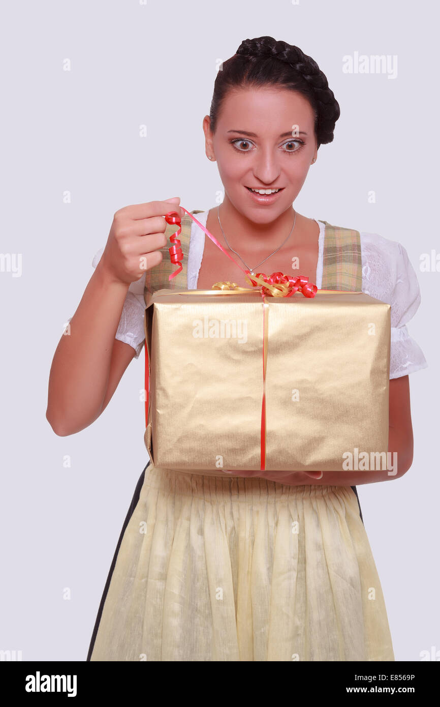 Junge Frau im bayerischen Dirndl packt ein Geschenk Stockfoto