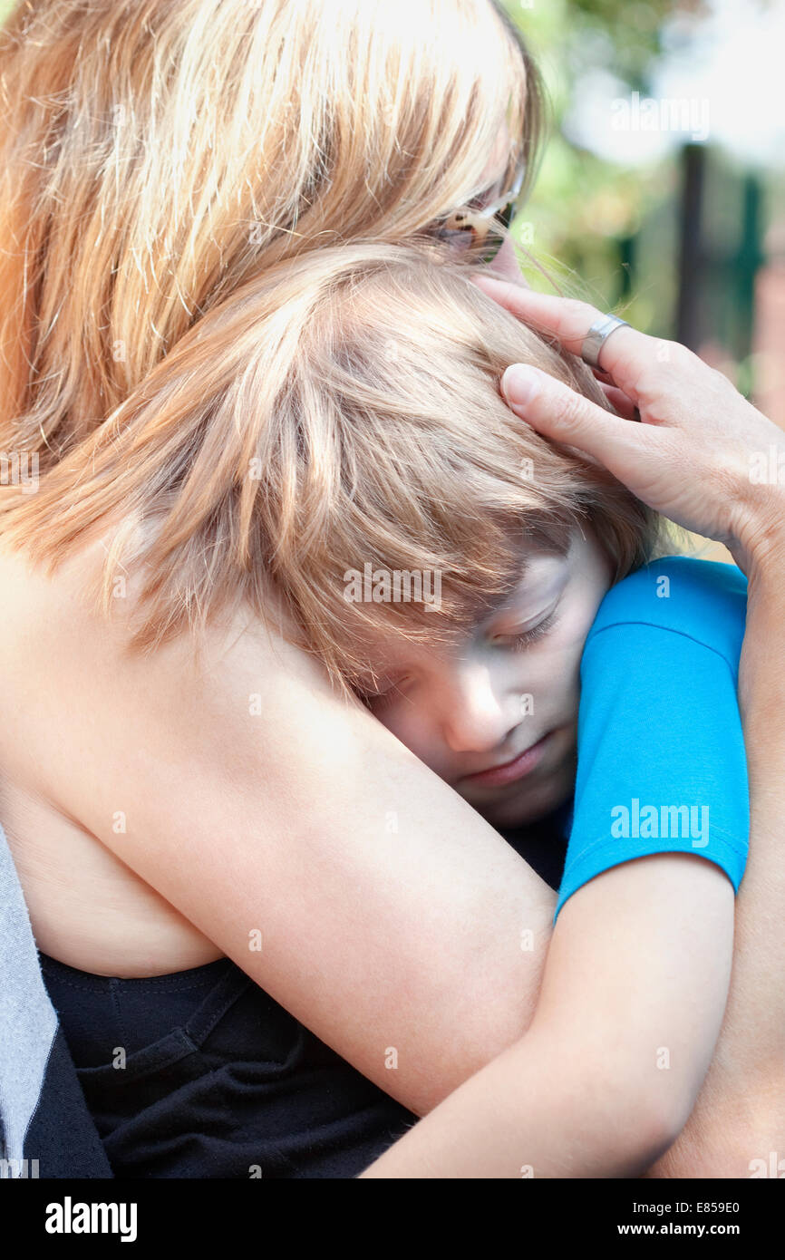 Junge umarmt seine Mutter sitzt auf ihrem Schoß schlafen Stockfoto