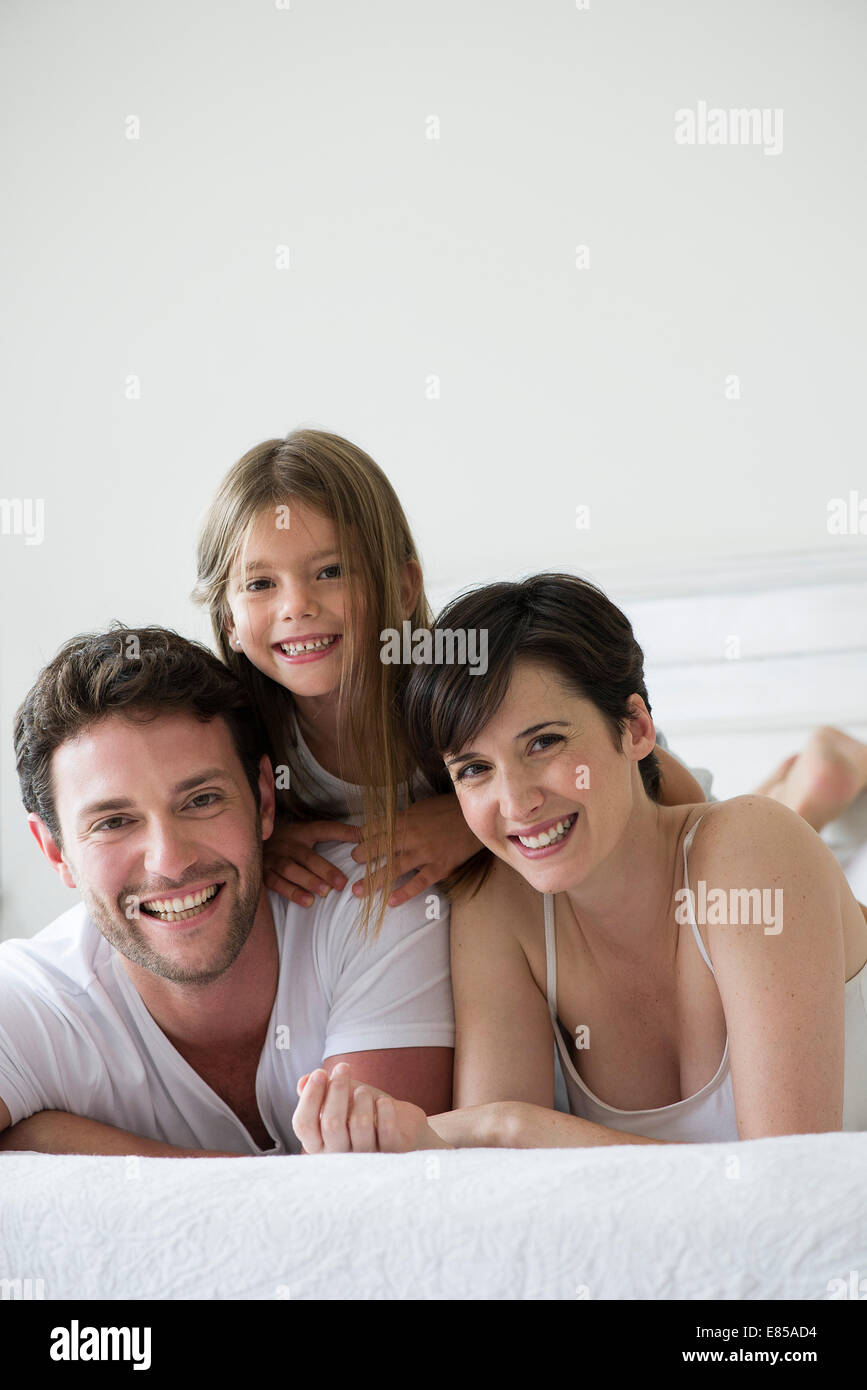 Eltern und Tochter gemeinsam auf Bett liegend, portrait Stockfoto