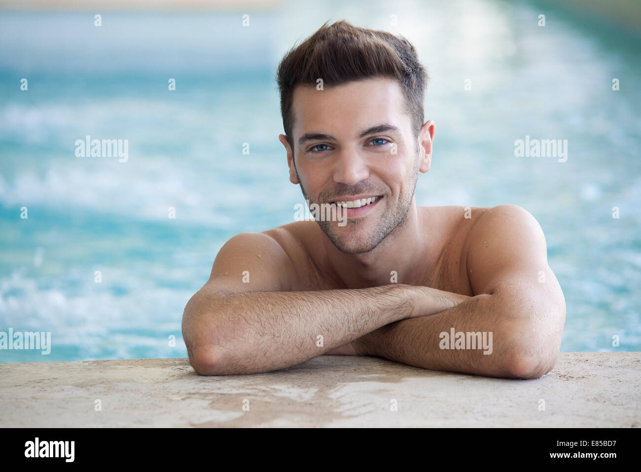 Junger Mann im Pool an Wand Stockfoto