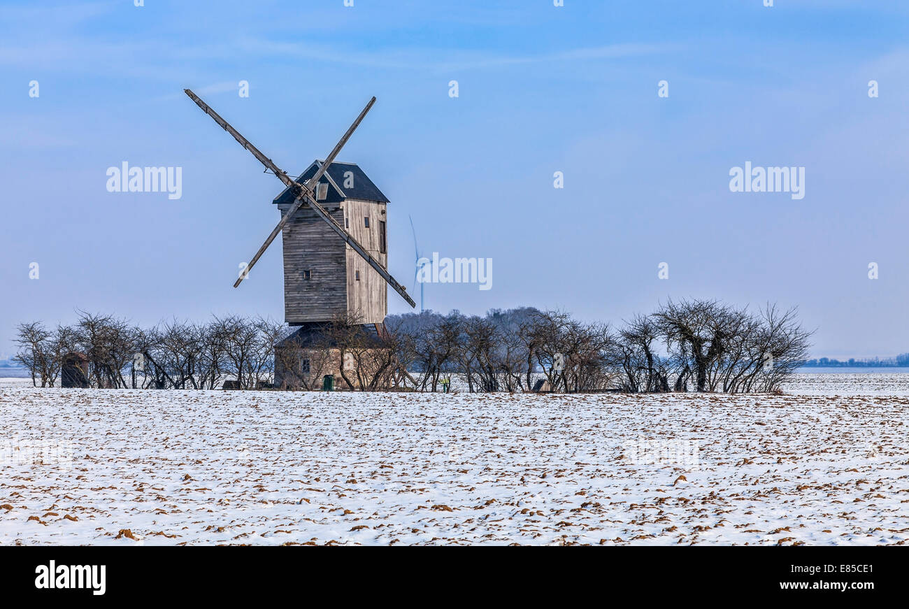 Winterlandschaft in der zentralen Region von Frankreich, mit einem traditionellen hölzernen Windmühle und einer modernen Windkraftanlage in der Ferne Stockfoto