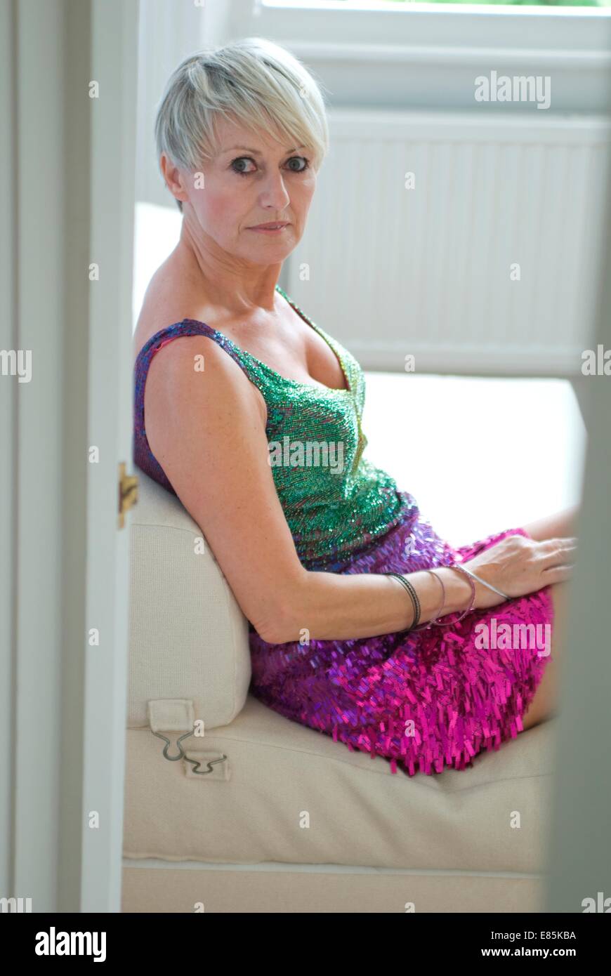 Reife Frau sitzt kurz Abendkleid Stockfoto