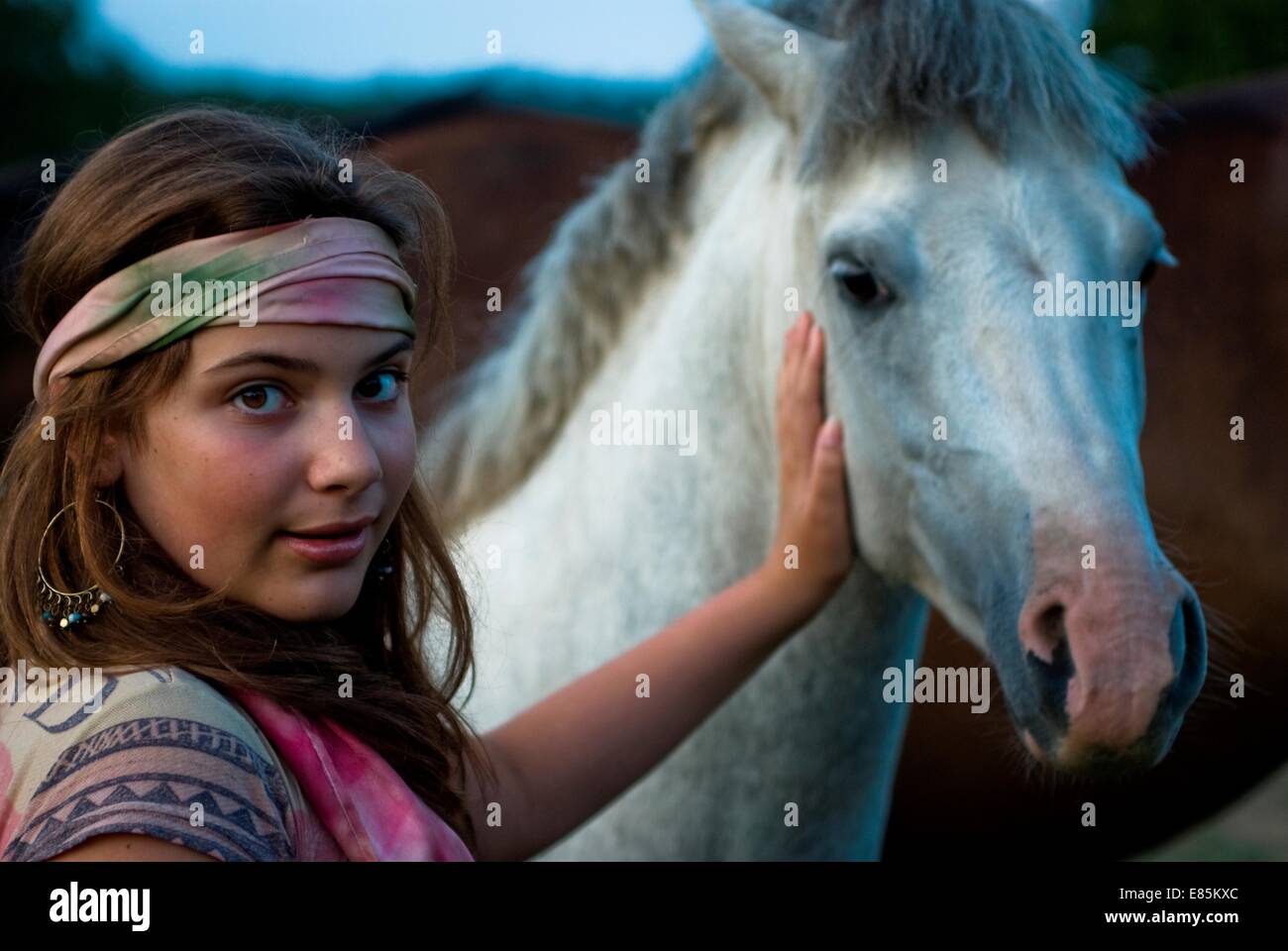 Teenager-Mädchen in Stirnband klopfte ein weißes Pferd Stockfoto