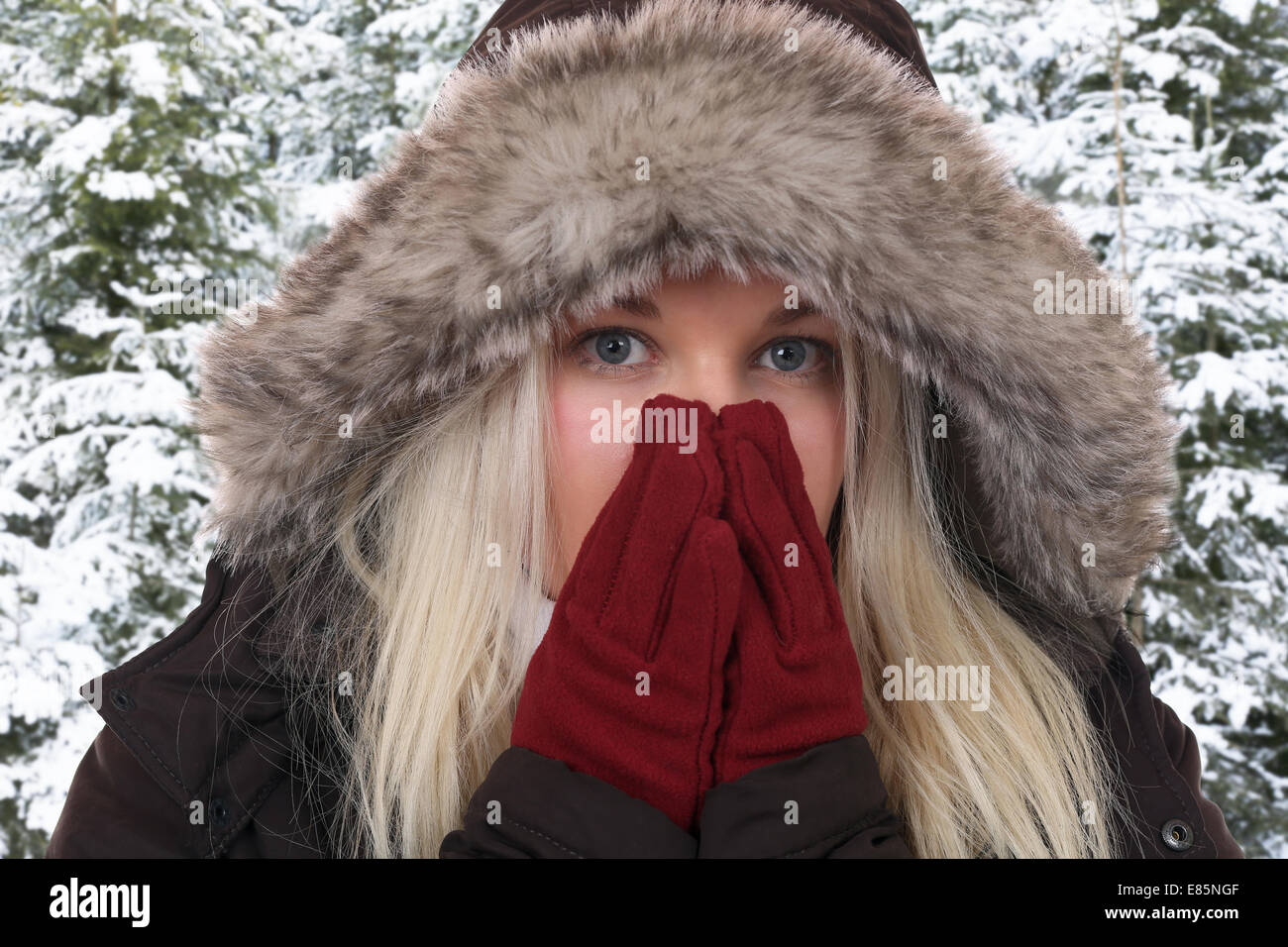 Junge Frau frieren in der Kälte im Winter in den Wäldern mit Handschuhe und Mütze Stockfoto