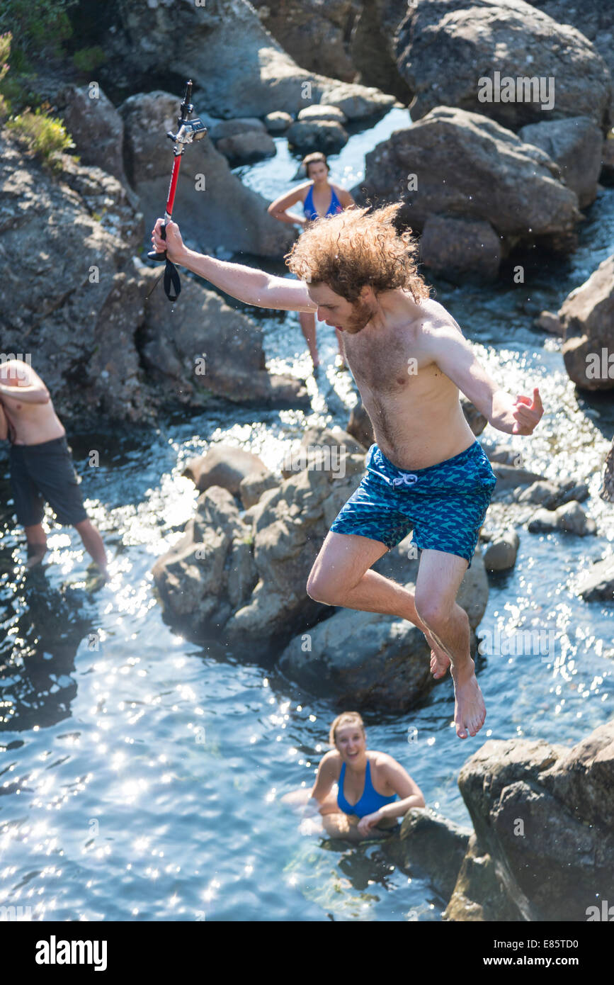 Mann springt in den Märchen-Becken in den Cuillin Bergen auf der Isle Of Skye Schottland im Sommer halten Sie Go pro Kamera Stockfoto