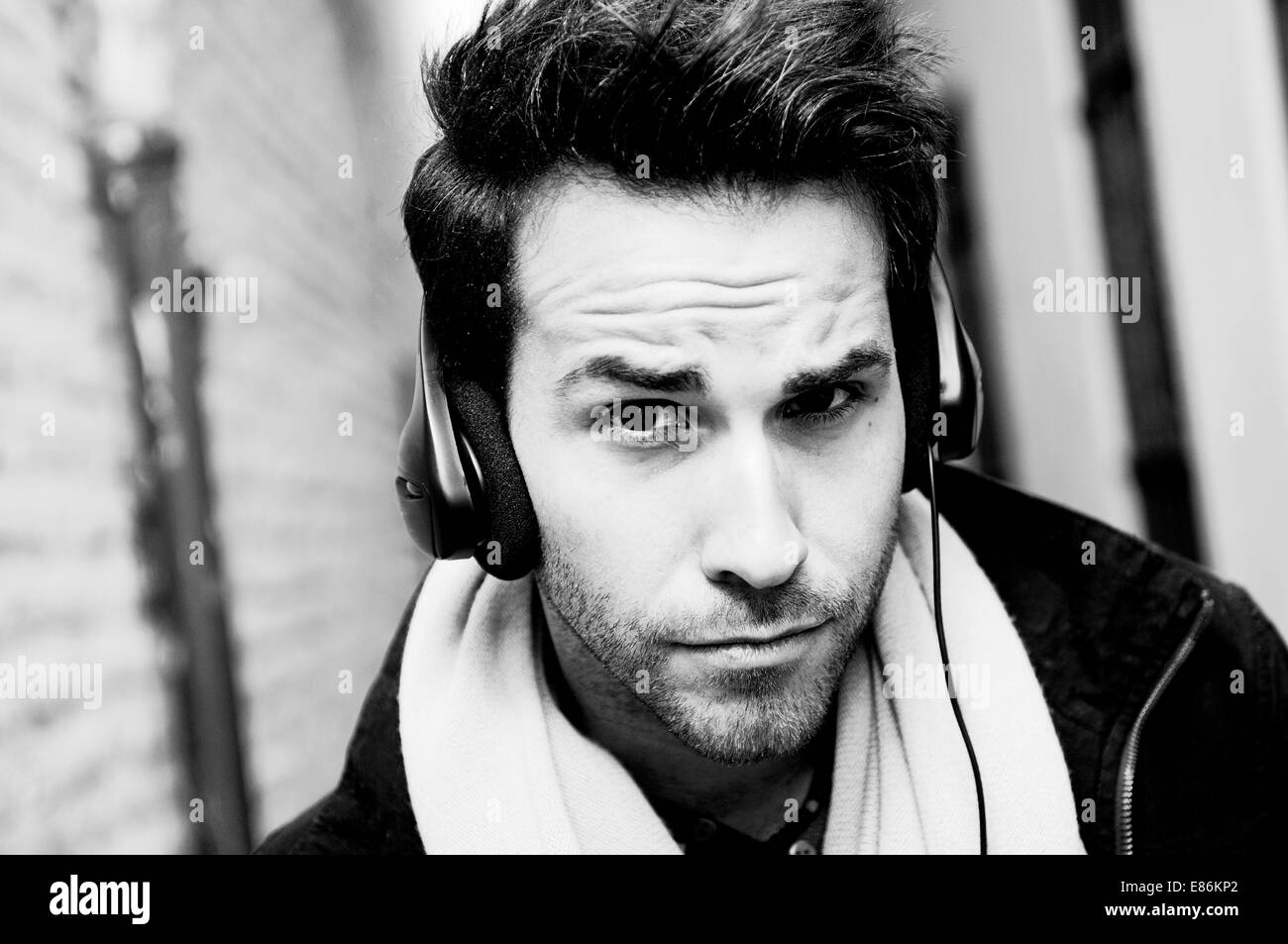Porträt von schöner Mann im städtischen Hintergrund Musikhören mit Kopfhörer Stockfoto