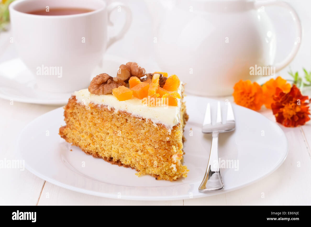 Karotte-Kuchen mit Zuckerguss und Tee auf weißer Holztisch Stockfoto