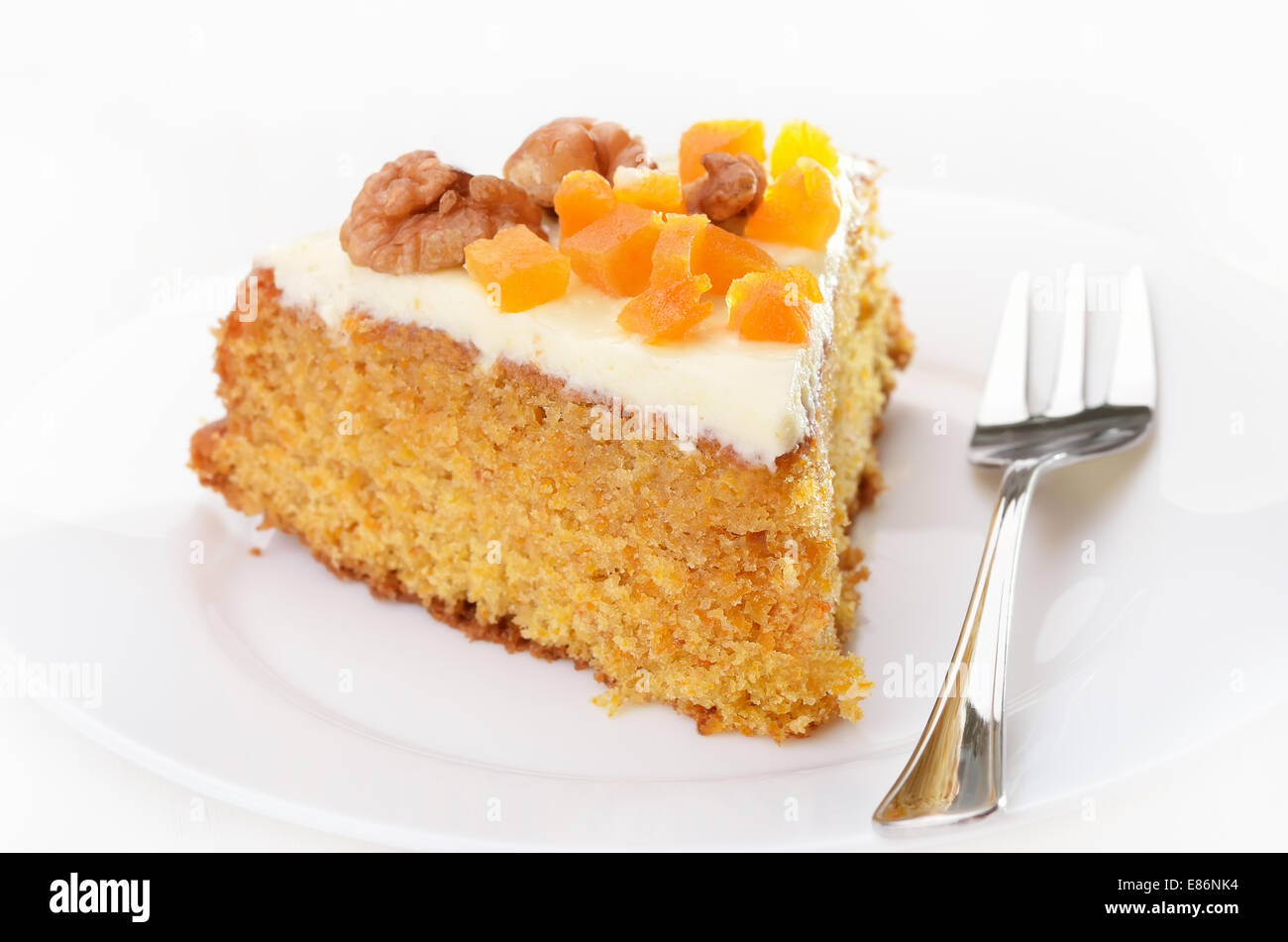 Karotte-Kuchen mit Zuckerguss verziert, getrockneten Aprikosen und Walnuss auf weißen Teller Stockfoto