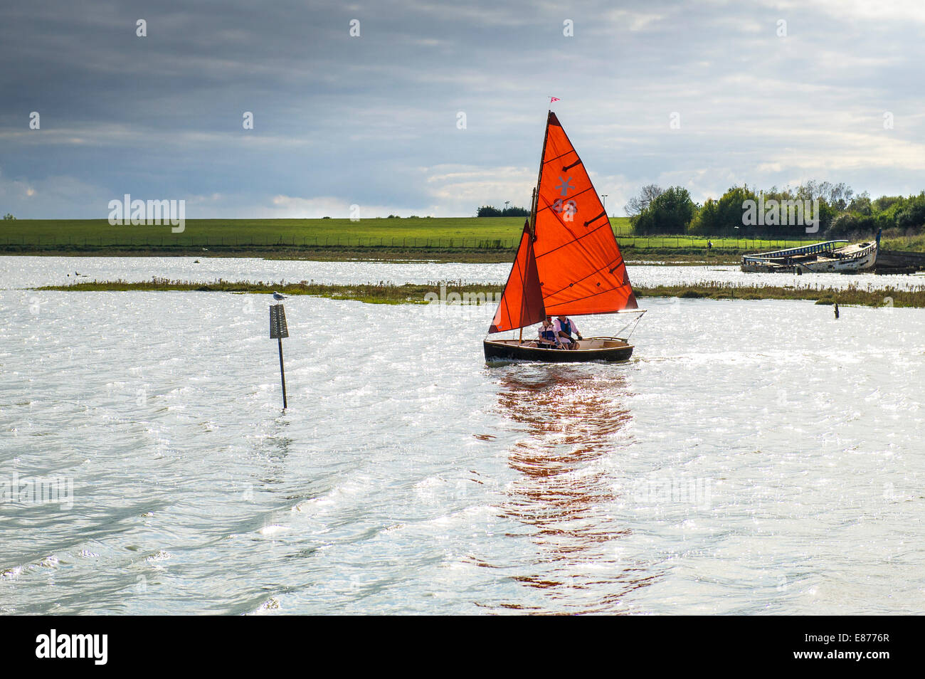 Eine kleine Jolle mit roten Segeln am Fluss Blackwater in Essex. Stockfoto