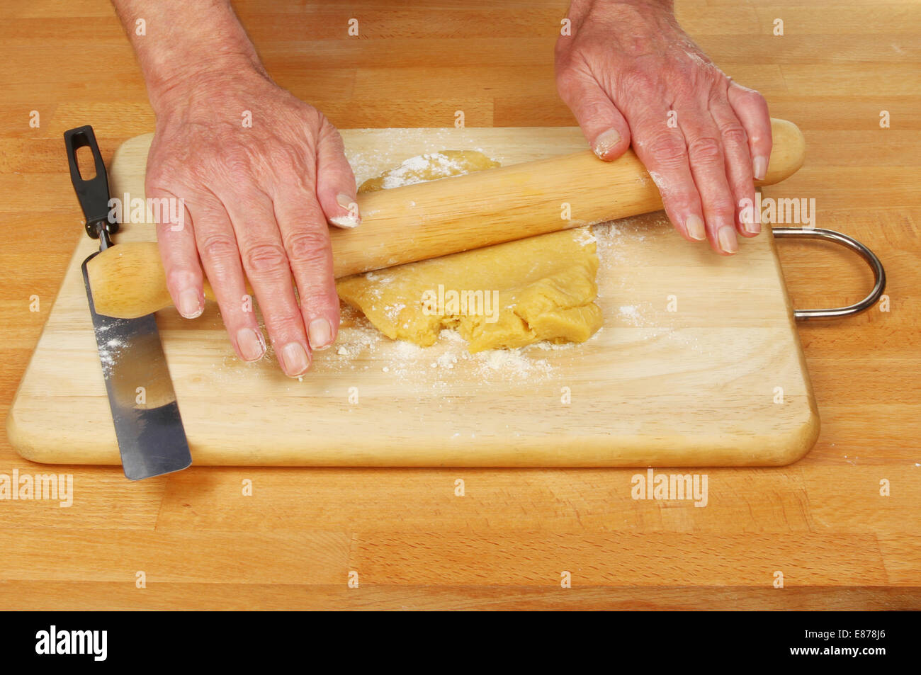 Hände, die Rollen von süßen Gebäck auf einem Brett und Arbeitsplatte Stockfoto