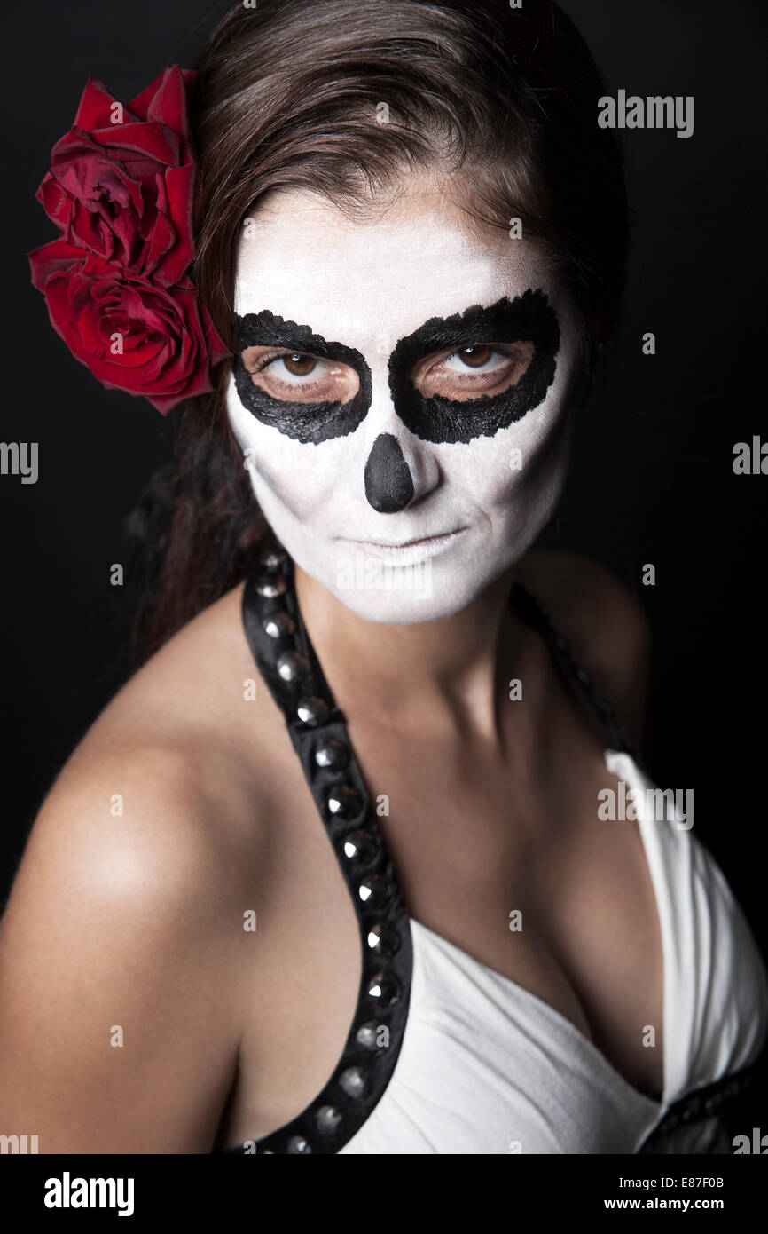 Frau mit Make-up von la Santa Muerte mit roten Rosen vor schwarzem Hintergrund Stockfoto