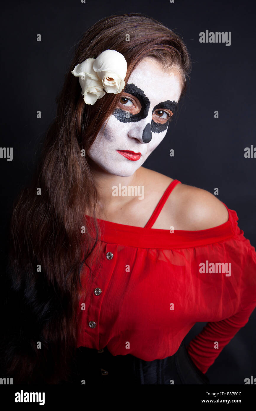 Frau mit Make-up von la Santa Muerte mit weißen Rosen vor schwarzem Hintergrund Stockfoto