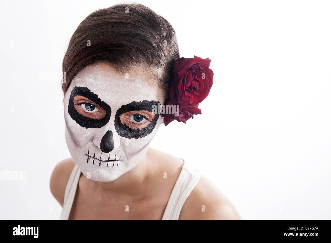 Frau mit Make-up von la Santa Muerte mit roten Rose vor einem weißen Hintergrund Stockfoto
