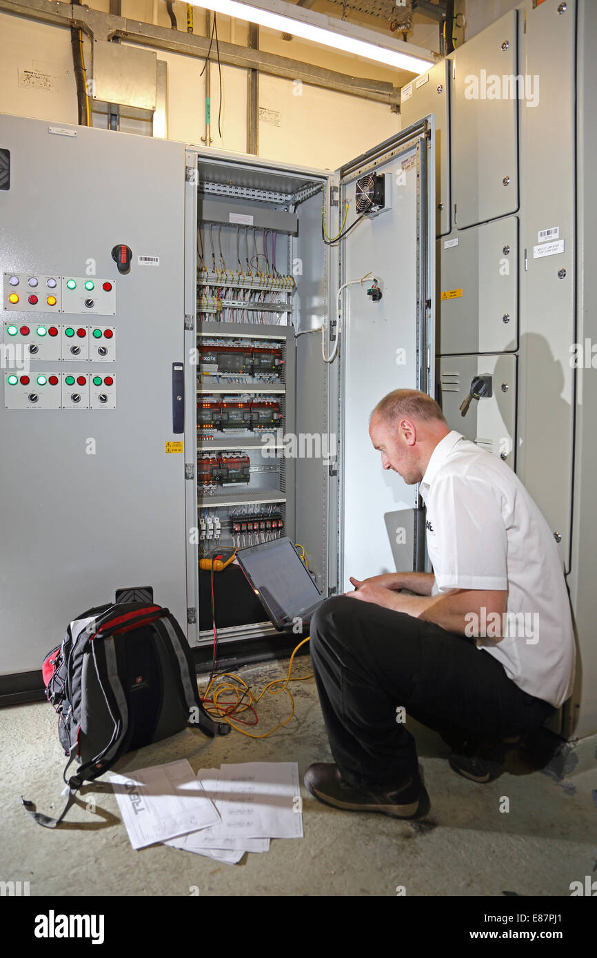 Ein Haustechnik Ingenieur Monitore elektrische Schaltschrank in den Maschinenraum eines großen Bürogebäudes mit einem computer Stockfoto