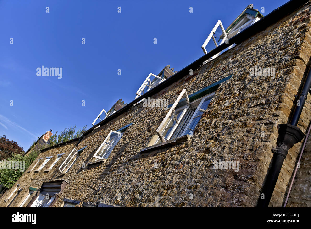 Cotswold-Steinhäuschen und holzgerahmte Fenster gegen einen leuchtend blauen Himmel an einem herrlichen Sommertag. England Großbritannien Stockfoto